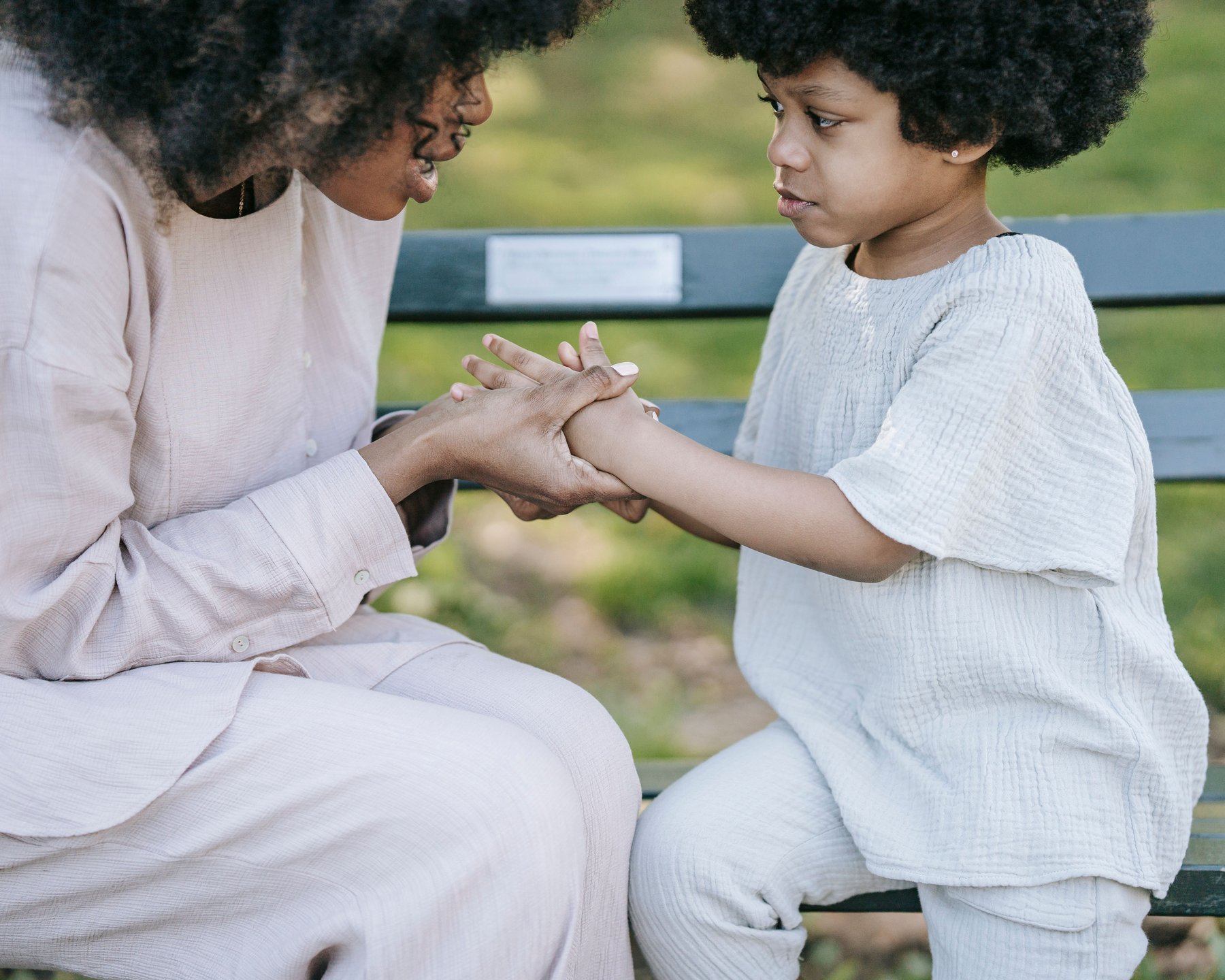 A woman warmly talking with a young girl, holding her hands