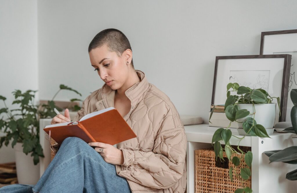 A woman smiling and writing thoughtfully in a diary